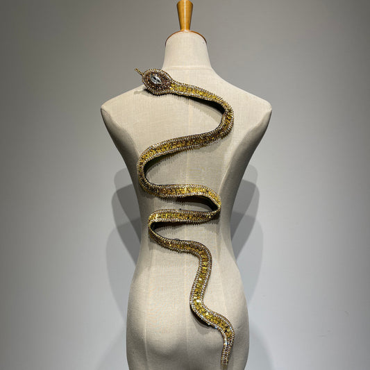 Handcrafted gold reputation snake patch on a mannequin featuring intricate sequins, gold beads, and sparkling crystal rhinestones.