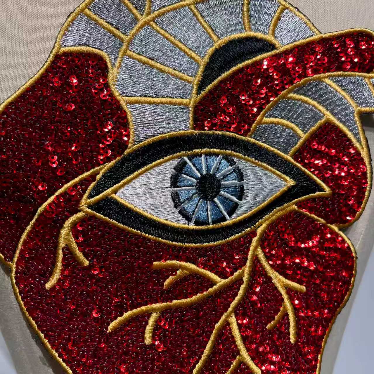 Extreme close-up showing the high-density red sequins, veins, and detailed third eye embroidery of the artisan patch.⁠