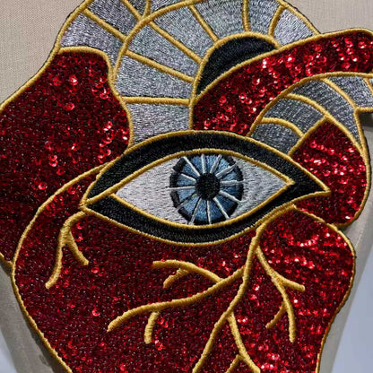 Extreme close-up showing the high-density red sequins, veins, and detailed third eye embroidery of the artisan patch.⁠