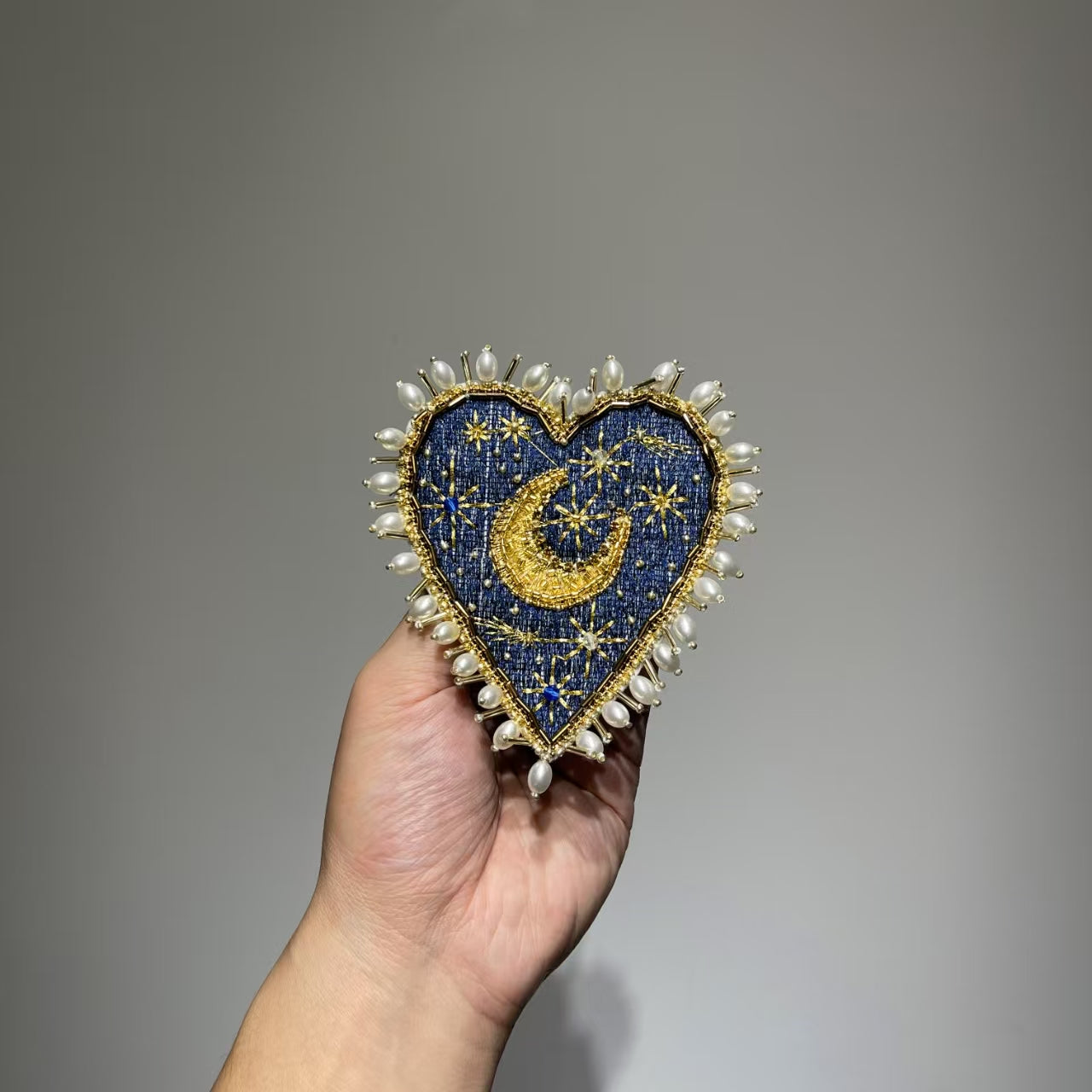 Front view of the 11.5x10cm Hand-Beaded Celestial Moon patch with a navy denim background, showcasing intricate gold thread stars, a gold embroidered crescent moon, and a luxury border of baroque pearls.