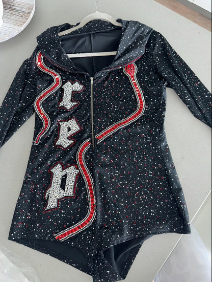 A black hooded bodysuit with silver rhinestone "REP" lettering on the chest and shimmering red sequined snakes on both sides, featuring a starry glitter fabric finish.⁠
