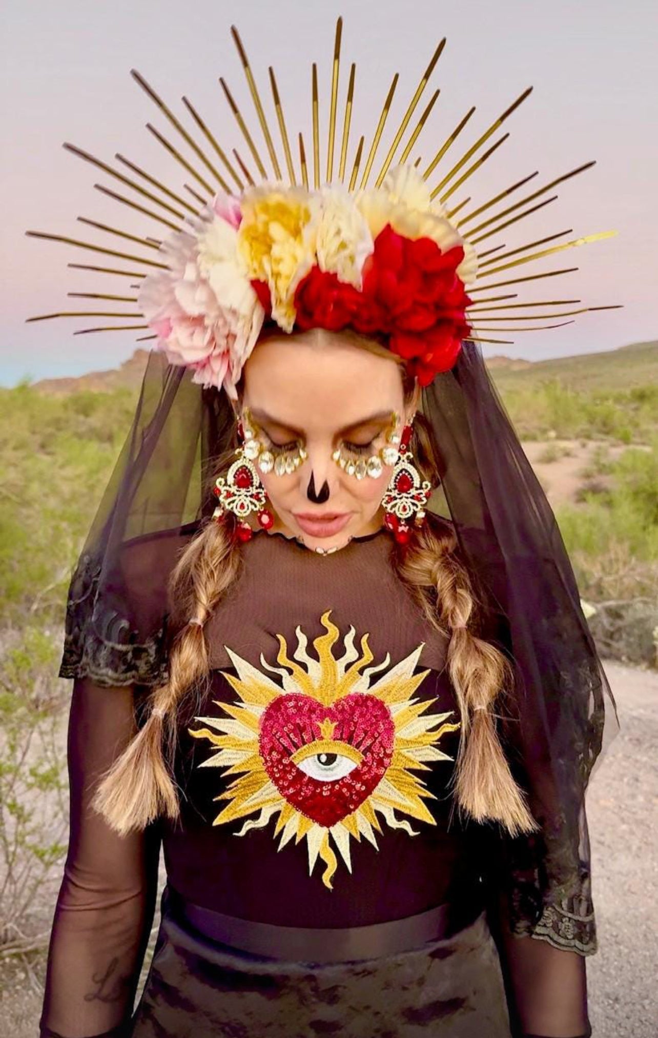 Stunning customer review photo featuring a woman in a desert festival outfit, wearing a black mesh top customized with the baroque red sacred heart embroidery patch on the chest.