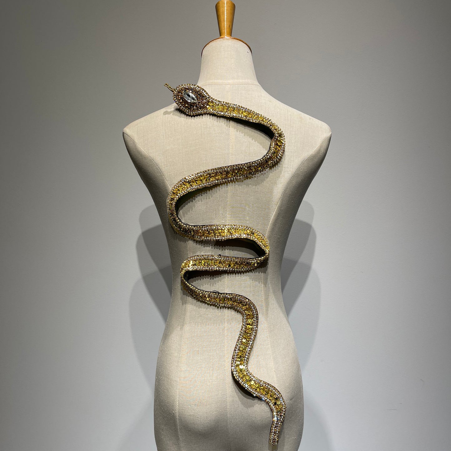 Handcrafted gold reputation snake patch on a mannequin featuring intricate sequins, gold beads, and sparkling crystal rhinestones.⁠