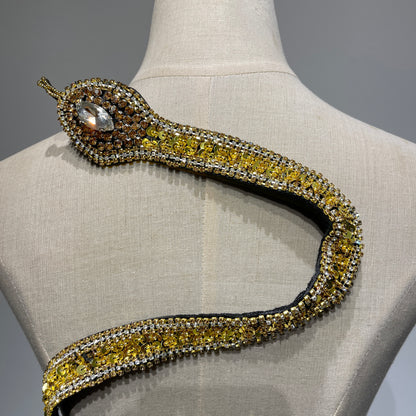 Close-up detail of a handcrafted gold snake patch head, featuring a large crystal eye, premium gold rhinestones, and meticulously hand-stitched sequins.