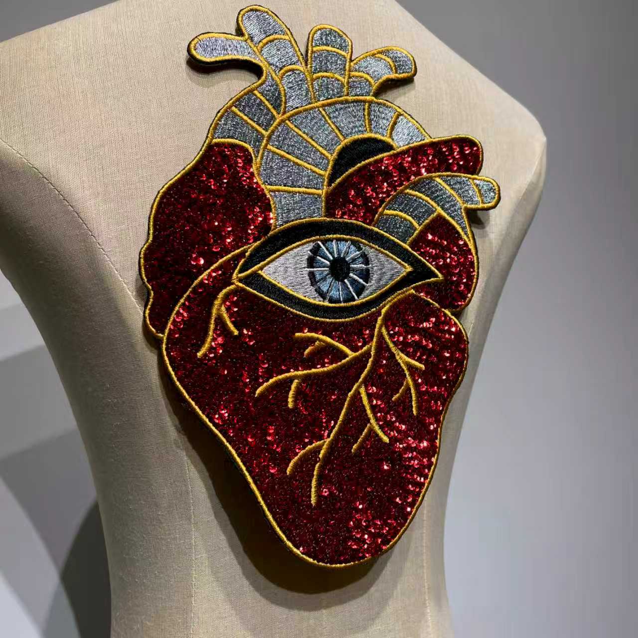 Side angle view highlighting the texture and metallic gold embroidery of the evil eye anatomical heart patch.⁠