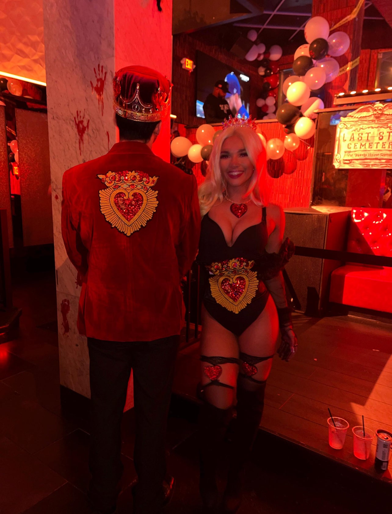Customer feedback photo showing a couple wearing matching DIY Halloween costumes decorated with the large Sacred Heart crown sequin patches on a red velvet blazer and a corset.⁠