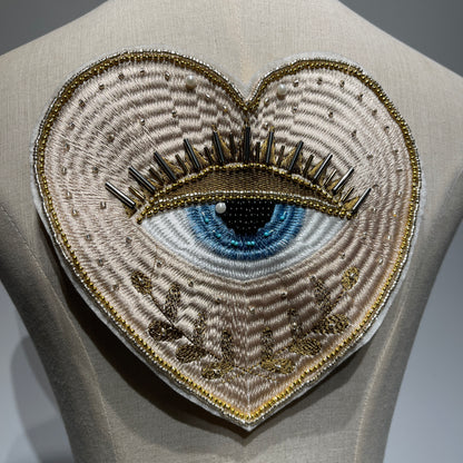 Close-up view of the luxury 19cm hand-beaded sacred heart evil eye patch on a mannequin, showcasing the intricate 3D bugle beads, seed beads, and premium metallic embroidery details.