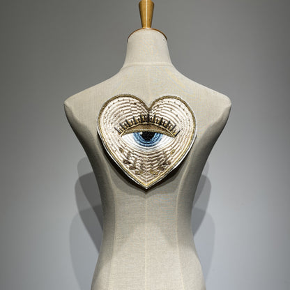 Luxurious 19cm hand-beaded sacred heart evil eye embroidery patch displayed on a clothing mannequin backpiece, showcasing 3D crystal bugle beads and metallic gold couture details for custom jacket DIY.