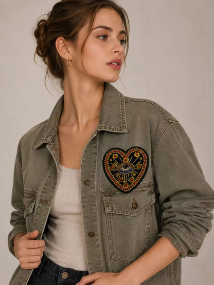 Model wearing an olive green denim jacket styled with a handmade black and gold rhinestone evil eye heart patch with red crystal beads and flower sequins - 10cm.