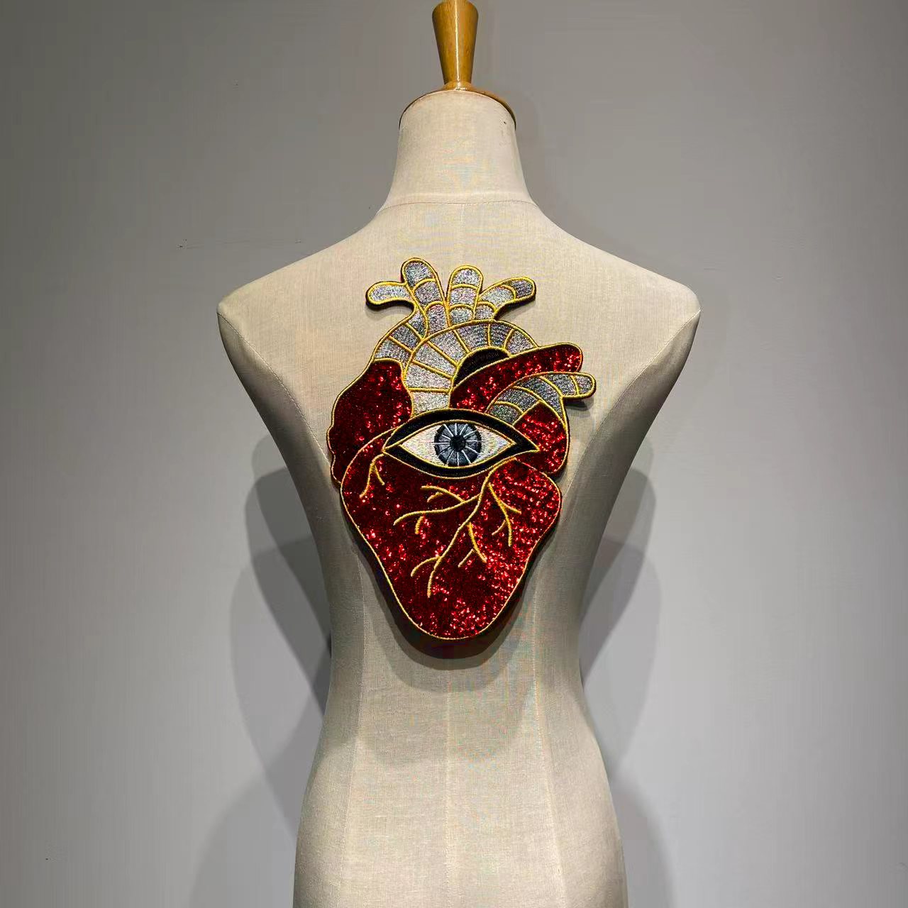 Oversized anatomical heart and evil eye sequin back patch on a mannequin denim jacket back.⁠