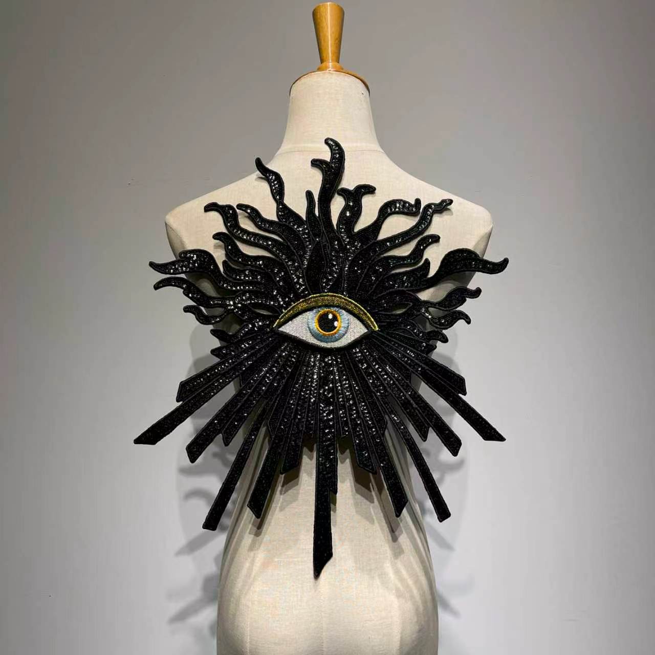 Oversized luxury black and gold evil eye sequin patch on a mannequin, handcrafted large embroidery back patch for jacket DIY custom fashion.