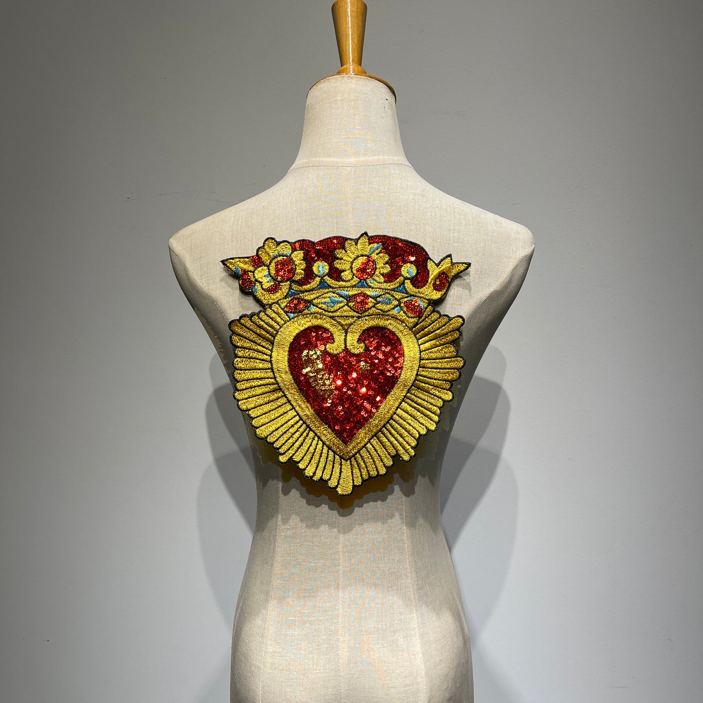 Large Sacred Heart and crown sequin embroidered back patch displayed on a mannequin torso, showcasing its scale for denim jackets.