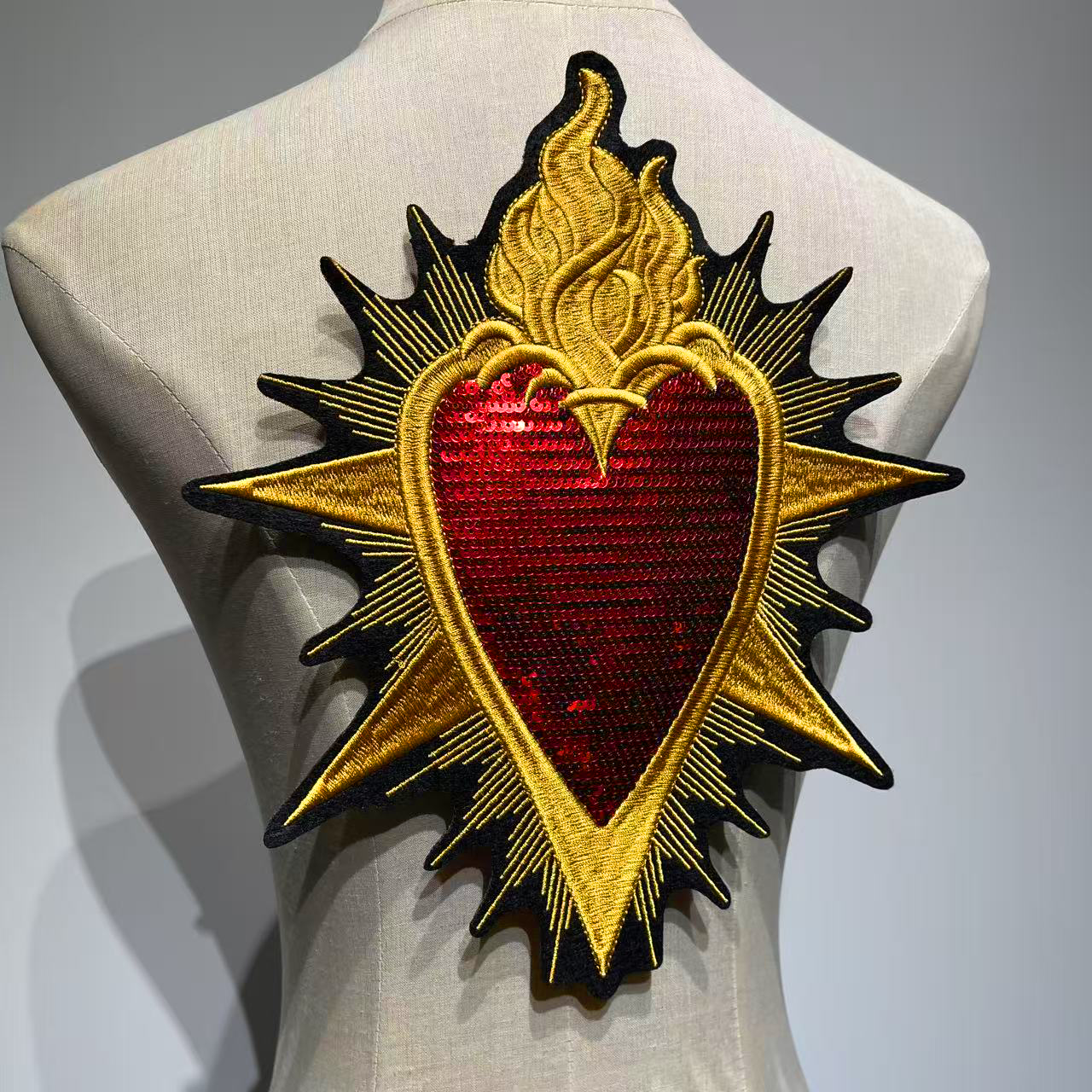 Side angle view of the oversized Baroque Sacred Heart backpiece patch styled on a dress form mannequin highlighting the shimmering texture and dimensional embroidery
