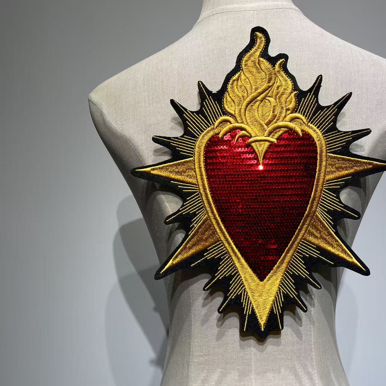 Full centered back view of the Sacred Heart sequin and embroidery patch on a mannequin demonstrating its large scale placement as a jacket backpiece