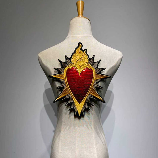 Oversized Sacred Heart embroidered jacket patch with shimmering red sequins and metallic gold baroque flames on a clothing mannequin back view