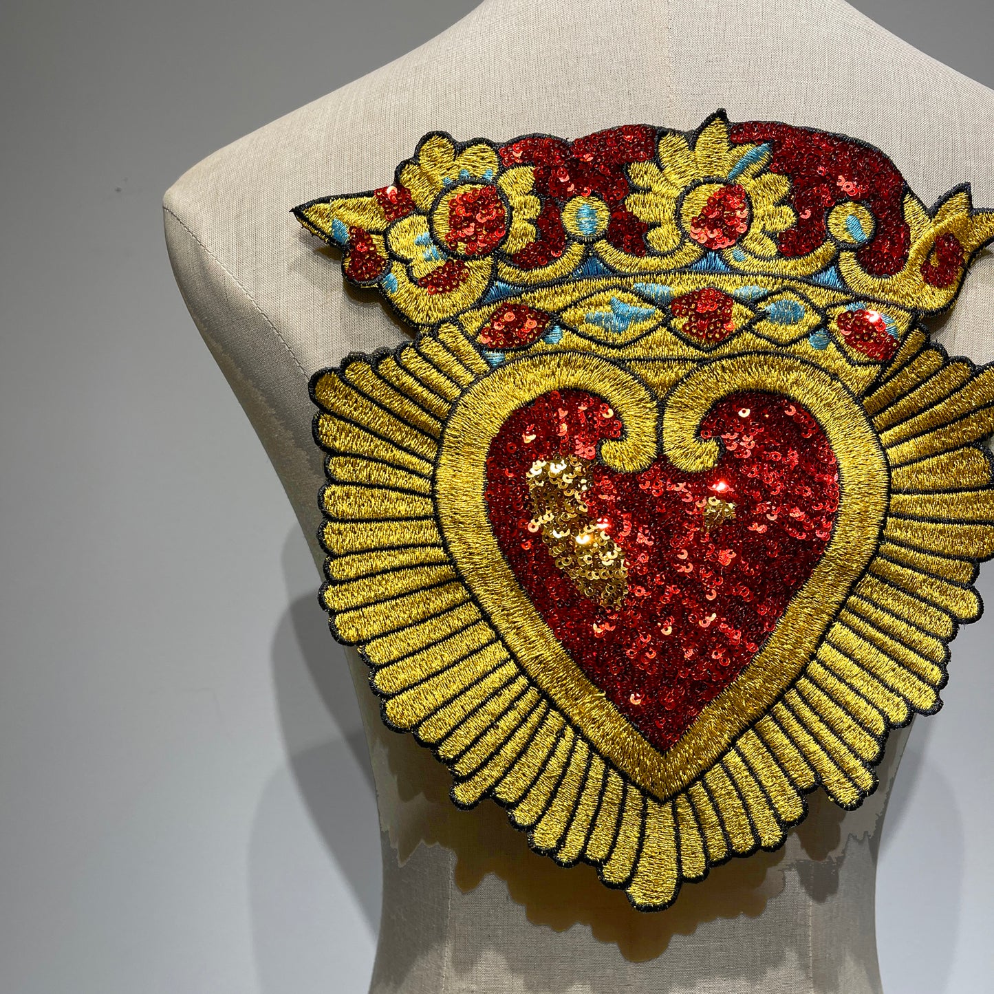 Close-up macro shot of the Sacred Heart patch, showing the high-density metallic gold embroidery threads and shimmering red and gold sequins.⁠