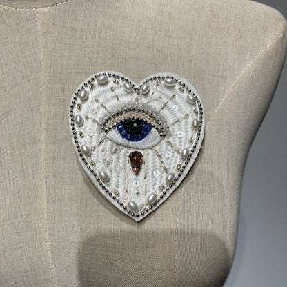 Mannequin display showcasing a handmade white evil eye beaded heart patch with pearls and sequins - 9.5x8cm.